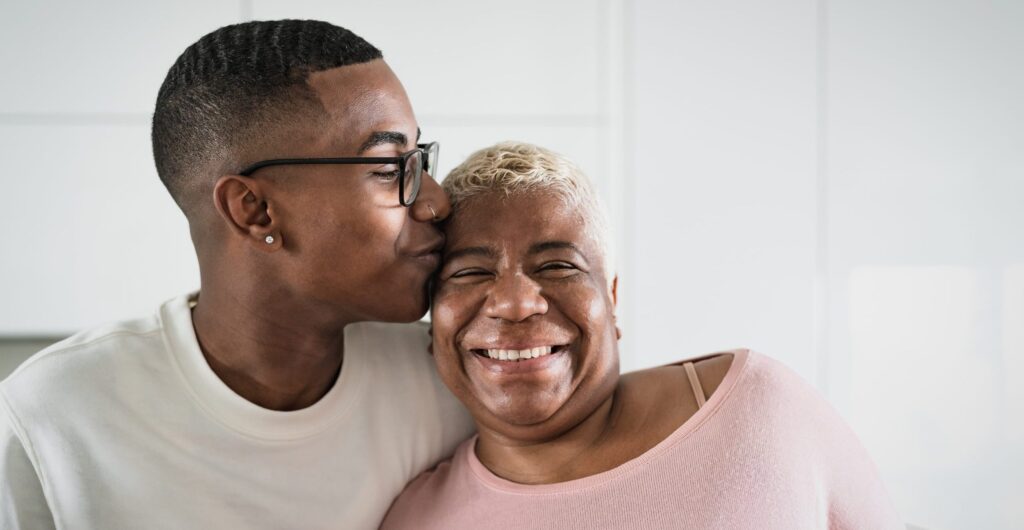 Adult son hugging his mom and giving her a kiss on the cheek