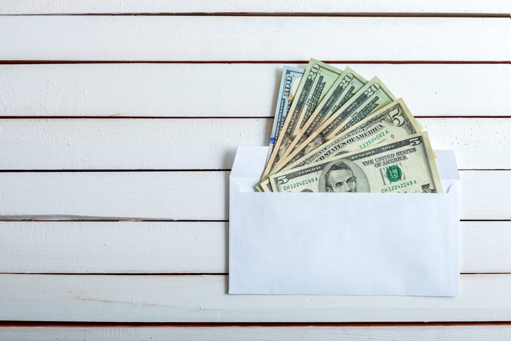 cash stuffing. Cash in an envelope, the denomination on a table from white wooden boards.