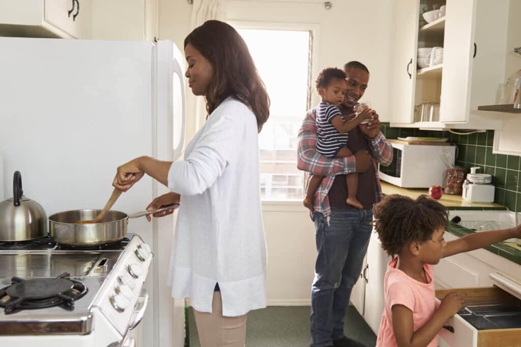 Black family in a kitchen preparing dinner. Article about creating a household budget.