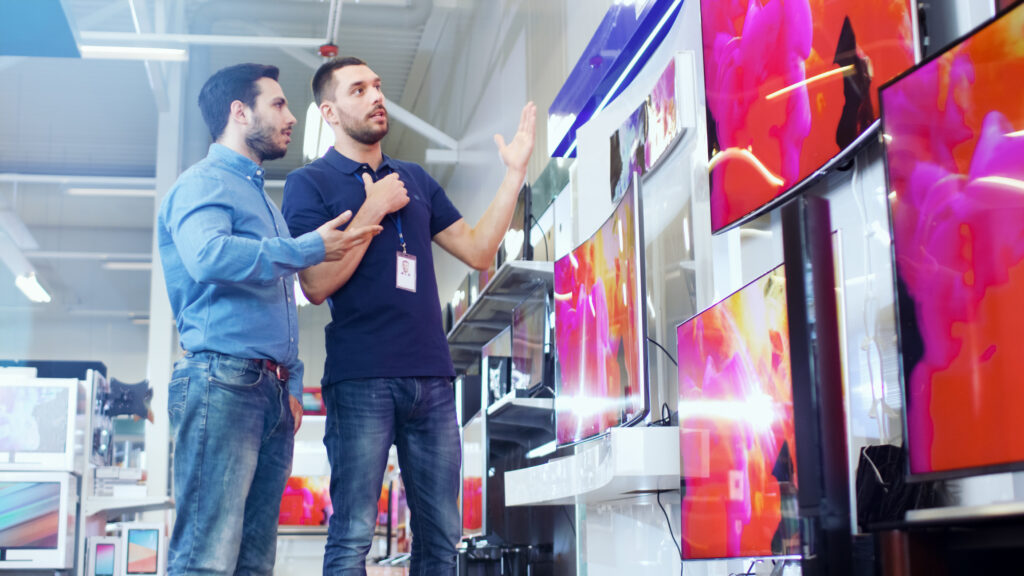 things you can negotiate. n the Electronics Store Professional Consultant Shows Latest 4K UHD TV's to a Young Man, They Talk about Specifications and What Model is Best for Young Man's Home. Store is Bright, Modern and Has all the Latest Models.