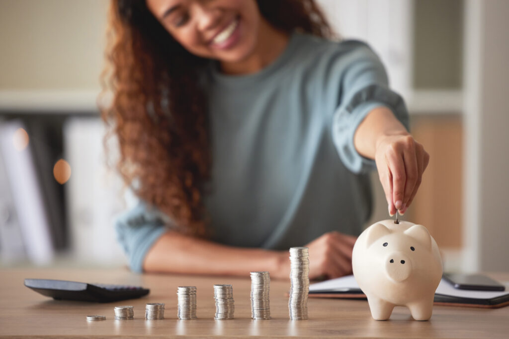 Young african american woman putting money in a piggy bank to save ,000 a year.