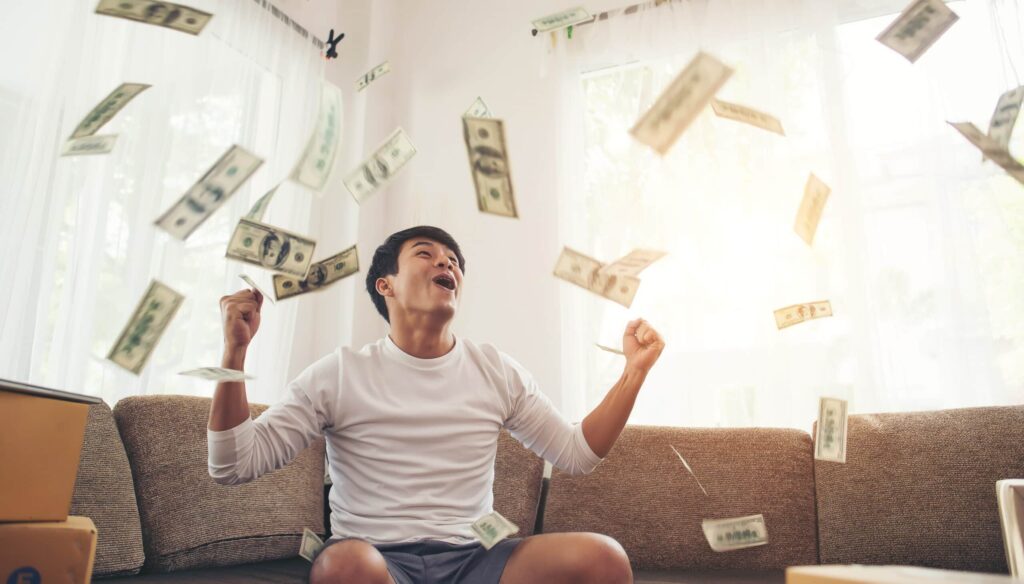 Man sitting on the couch with money falling