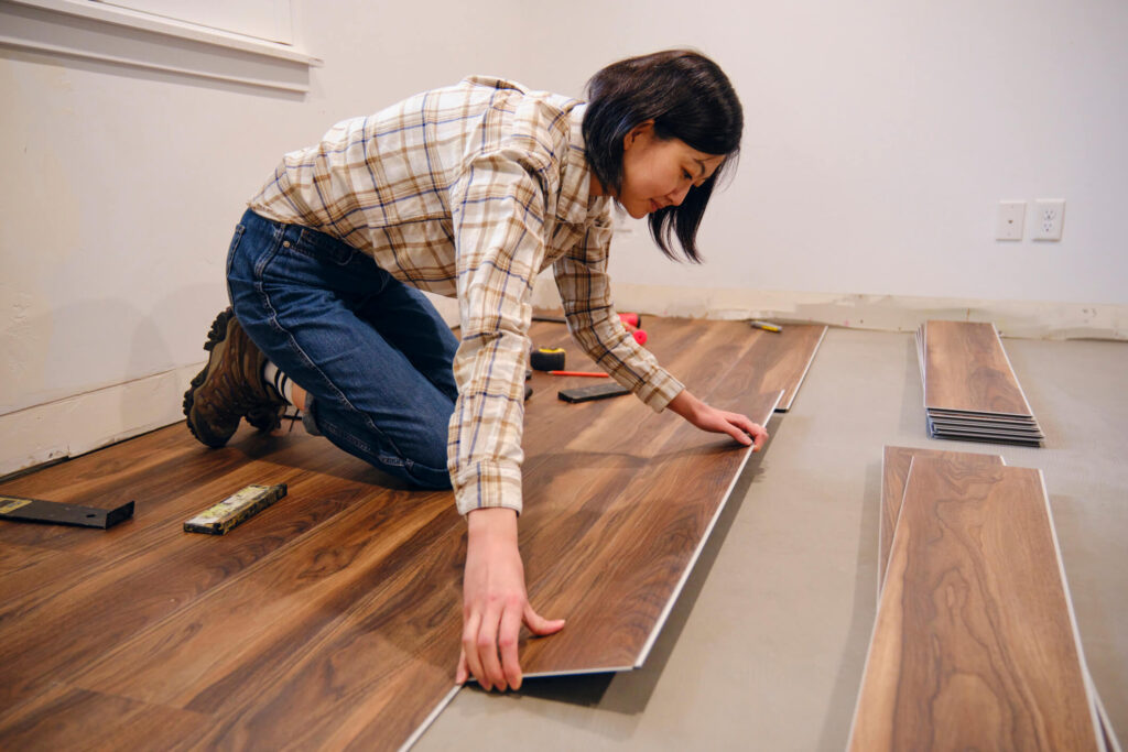 DIY home repair. A woman installing laminate flooring in her home.